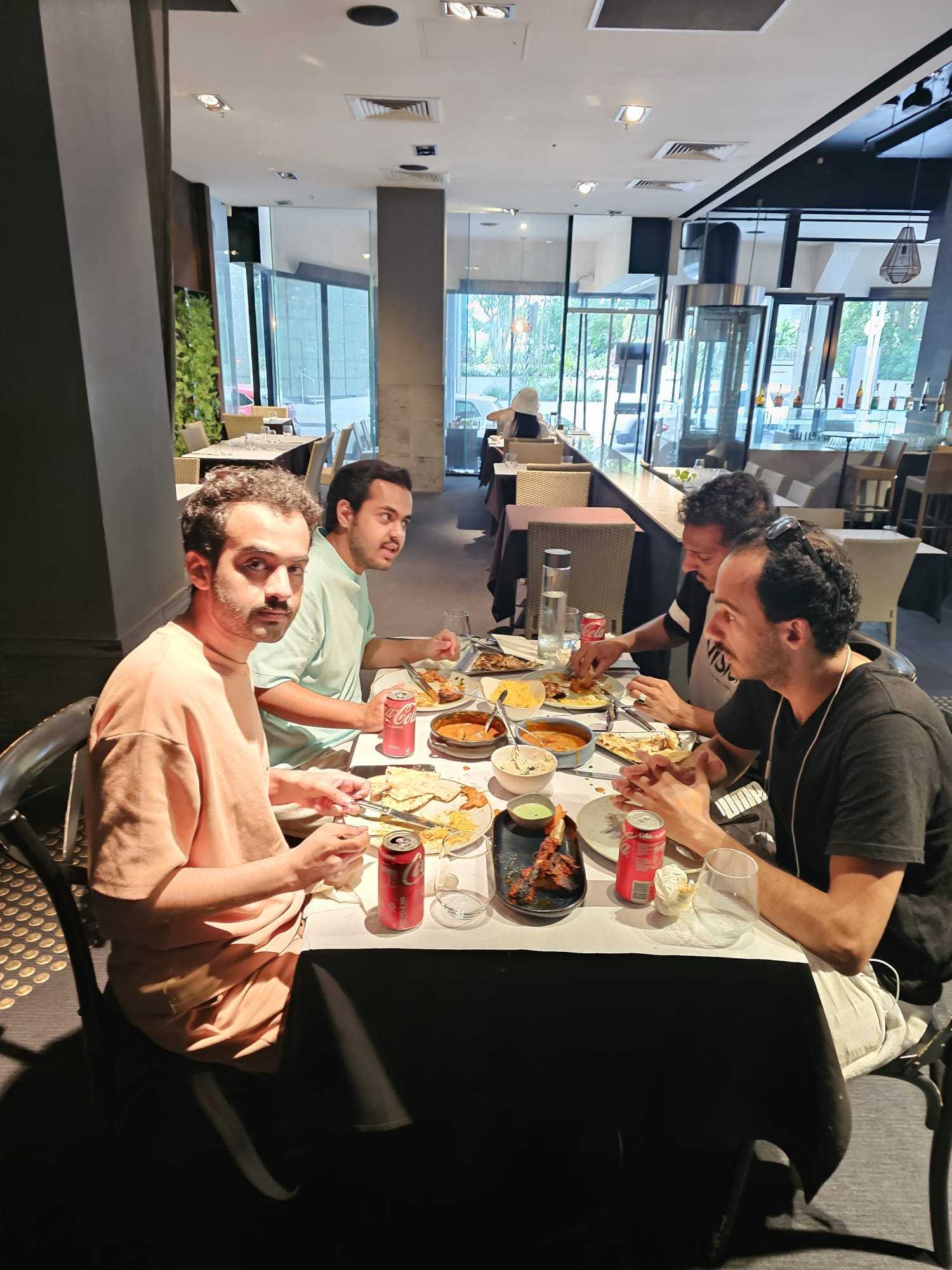 Four guests sharing curries and bread at a table