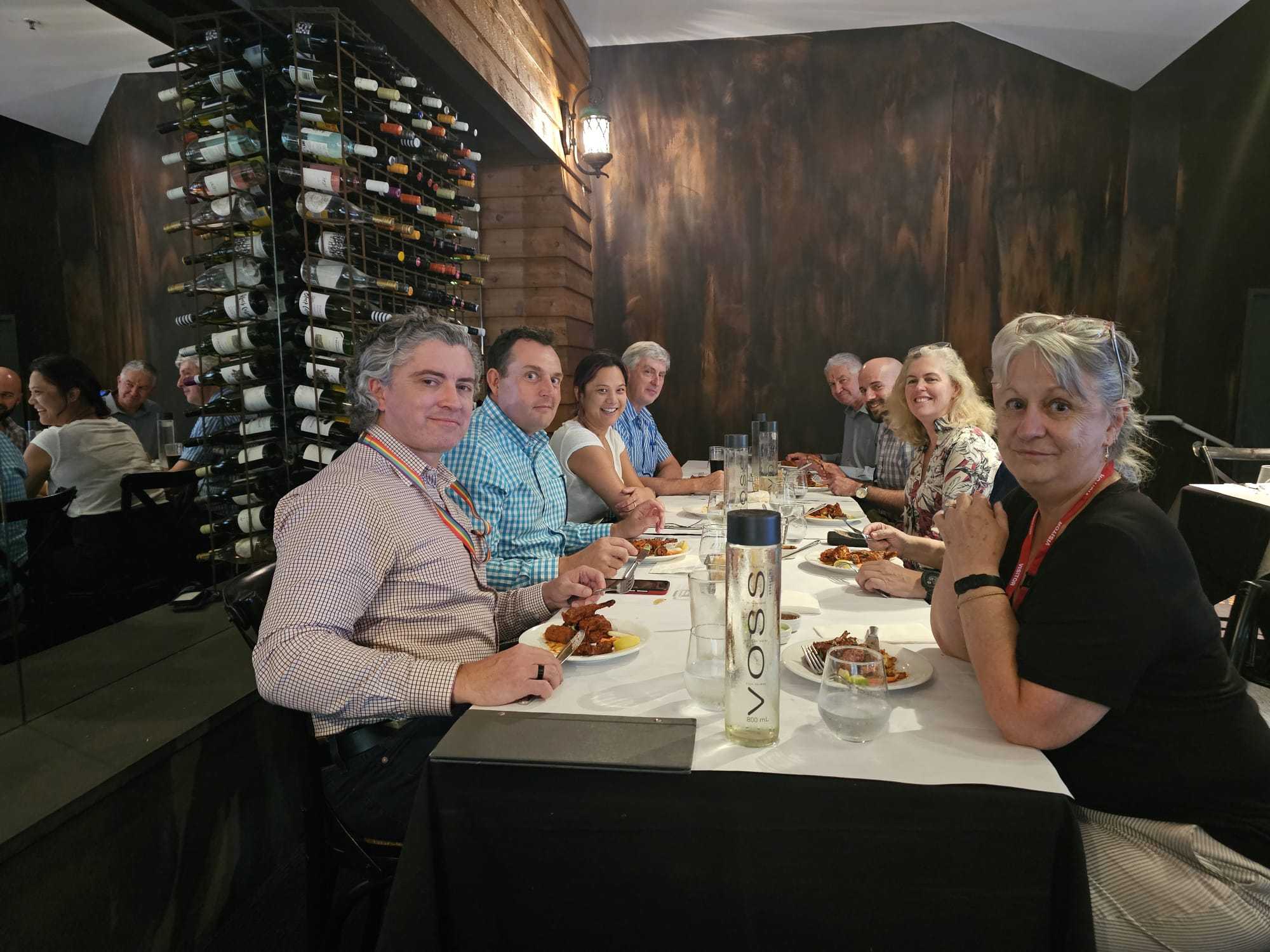 A large group dining beside the wine wall at Indian Mehek