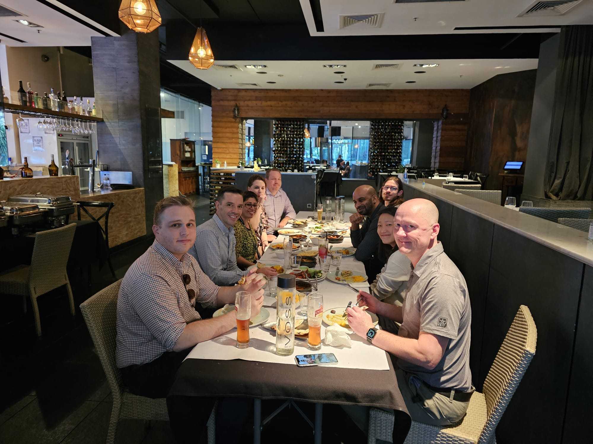 A group dining at a long table of Indian dishes at Indian Mehek