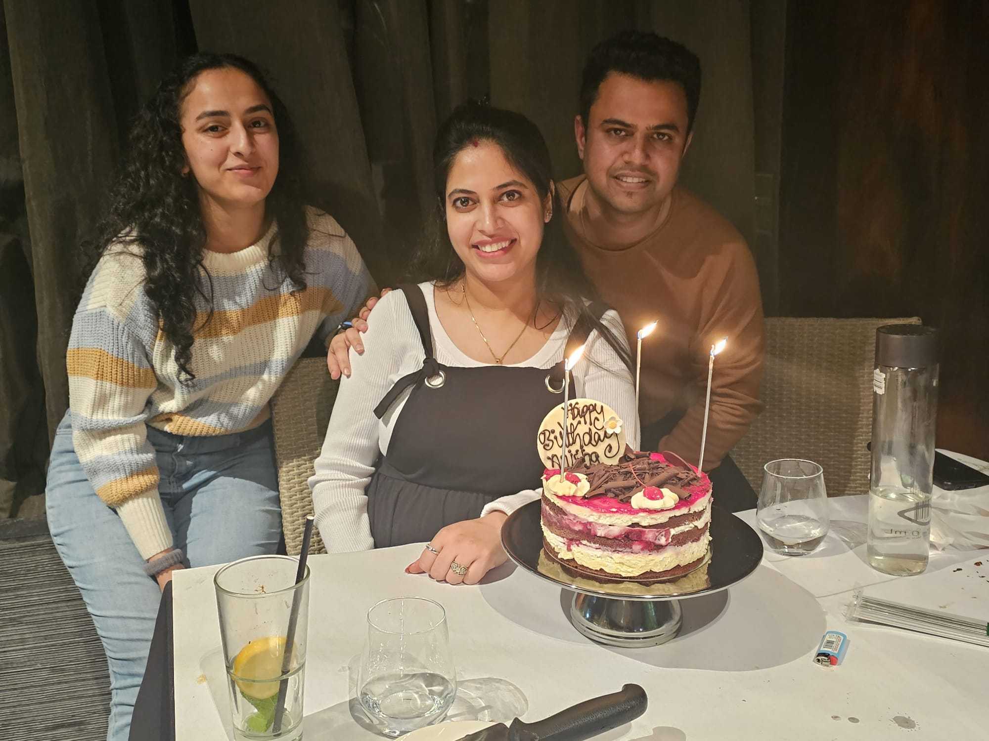 Three guests with a birthday cake at a table at Indian Mehek