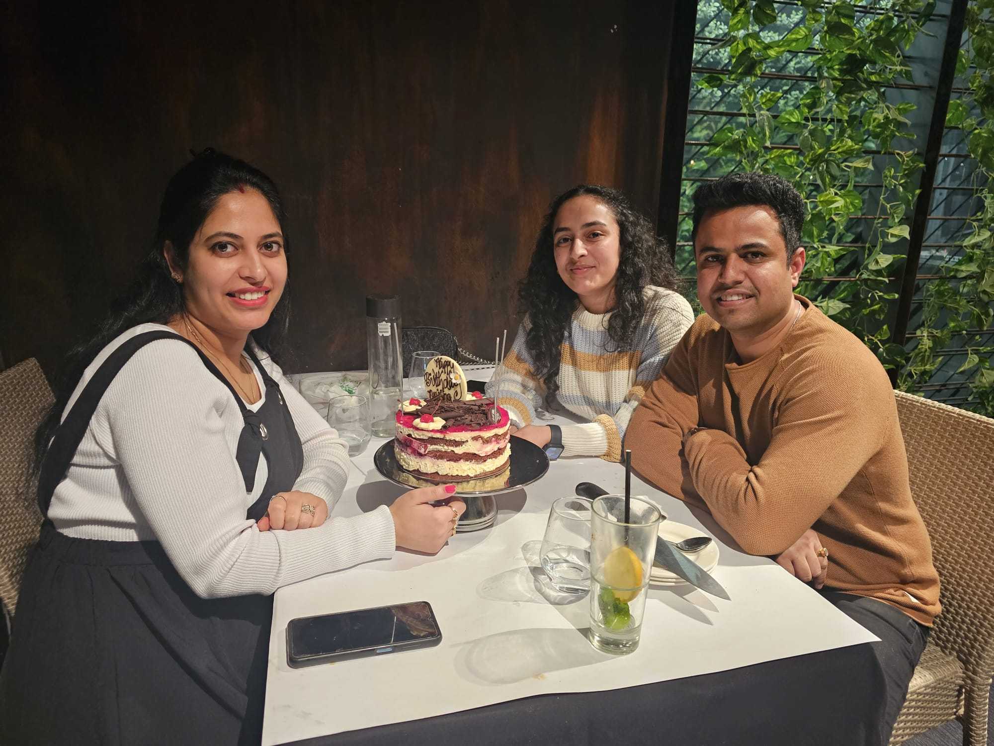Three guests seated with a birthday cake at Indian Mehek