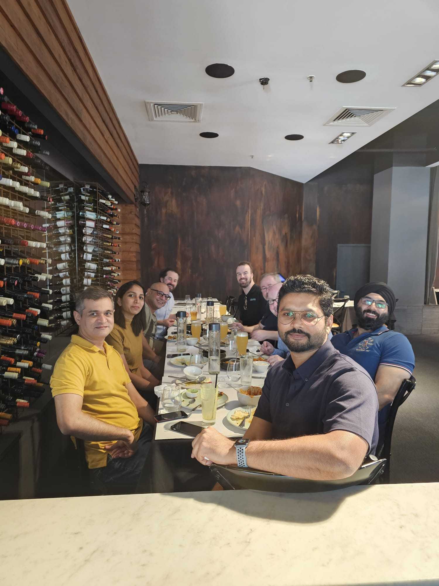 A group dining beside the wine wall at Indian Mehek