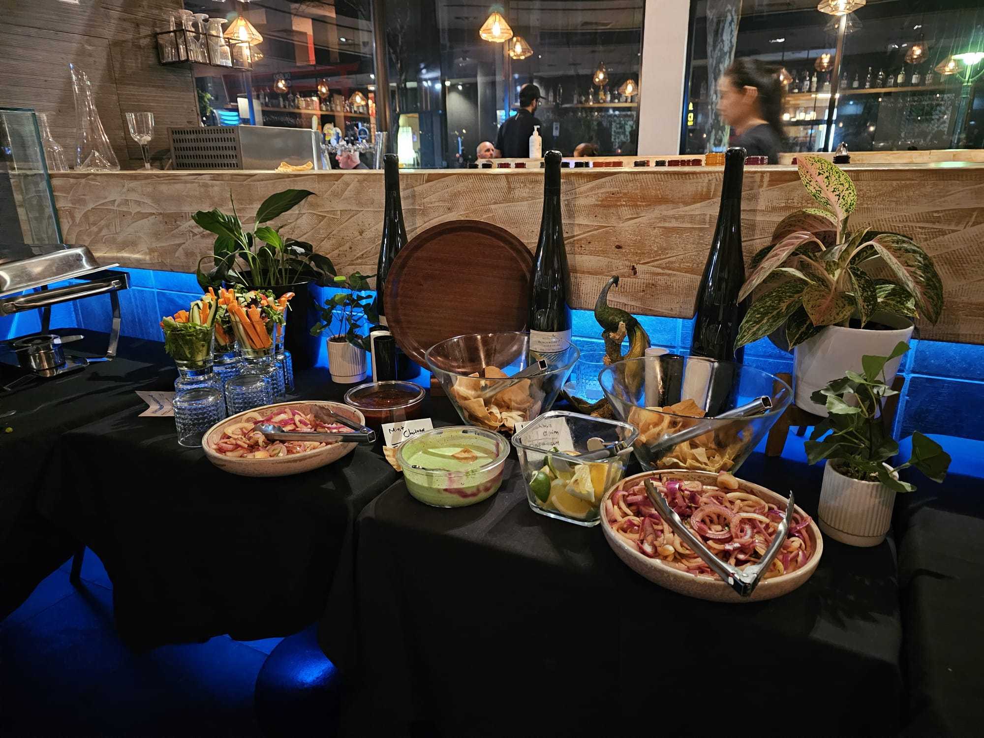 A buffet table of salads, papad, and chutneys at Indian Mehek